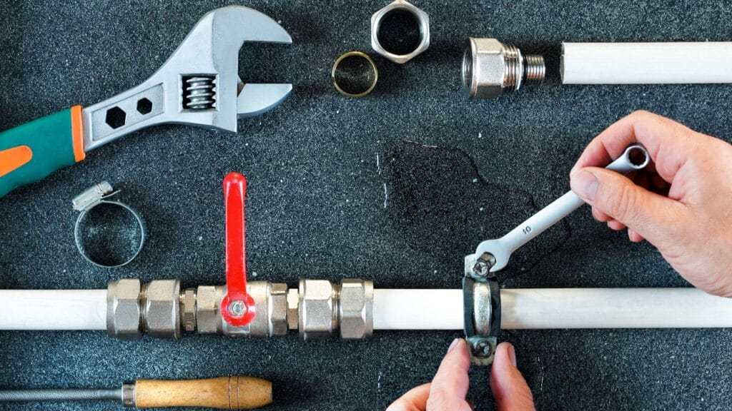 Plumber repairing a pipe valve with an adjustable wrench in Coral Gables