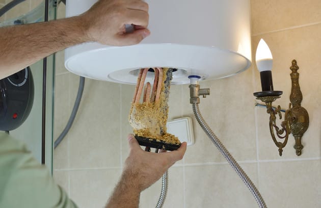 Technician removing mineral buildup from a water heater in Coral Gables