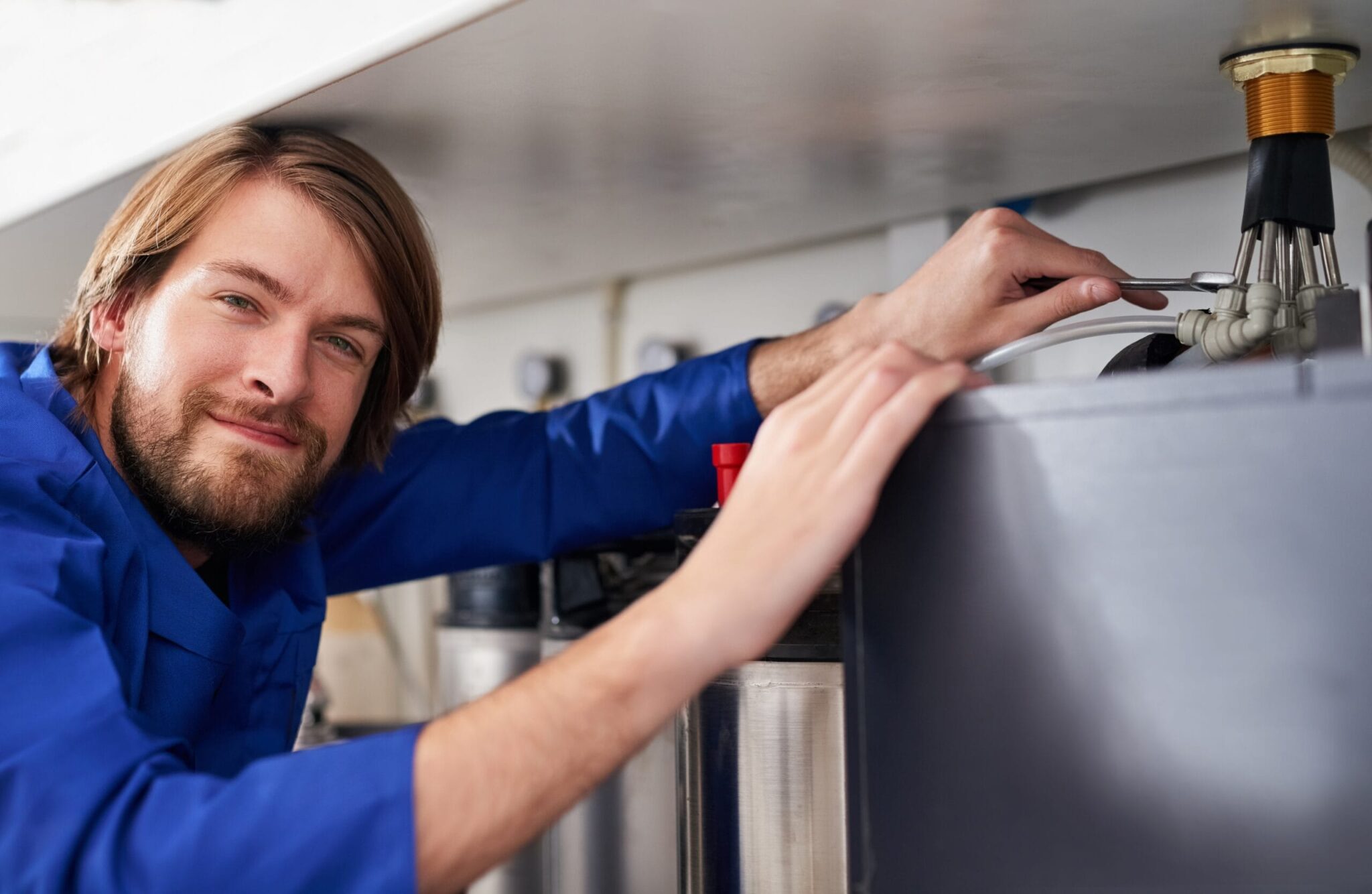 Technician servicing a residential water heater tank in Coral Gables
