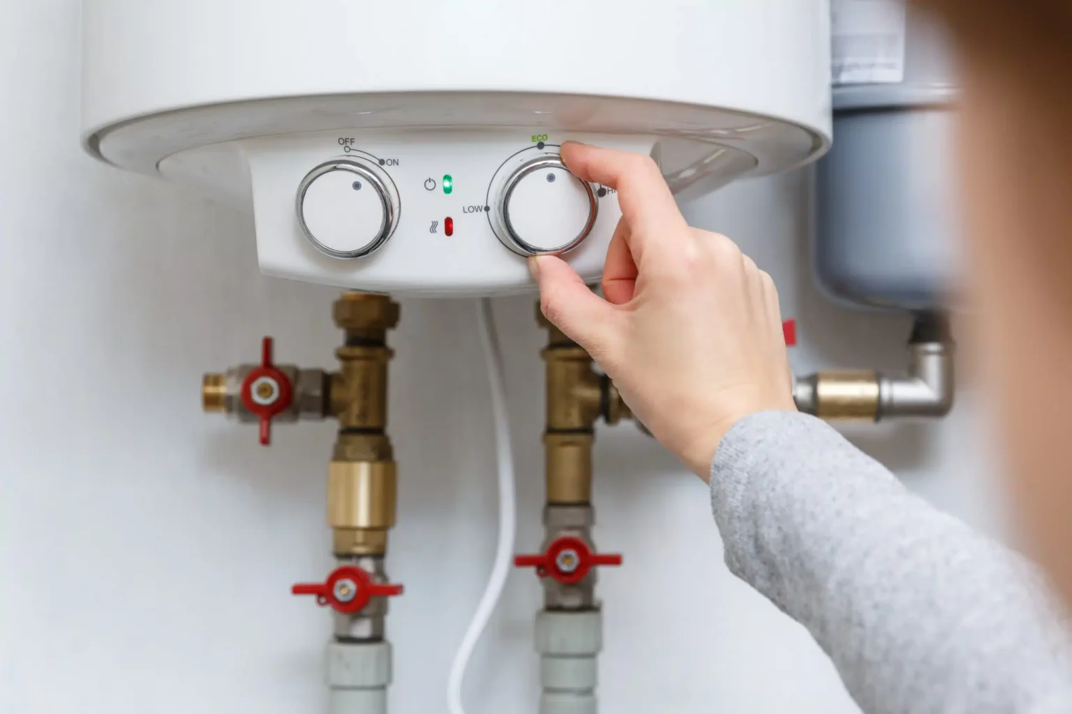 Homeowner adjusting the temperature controls on a water heater in Coral Gables